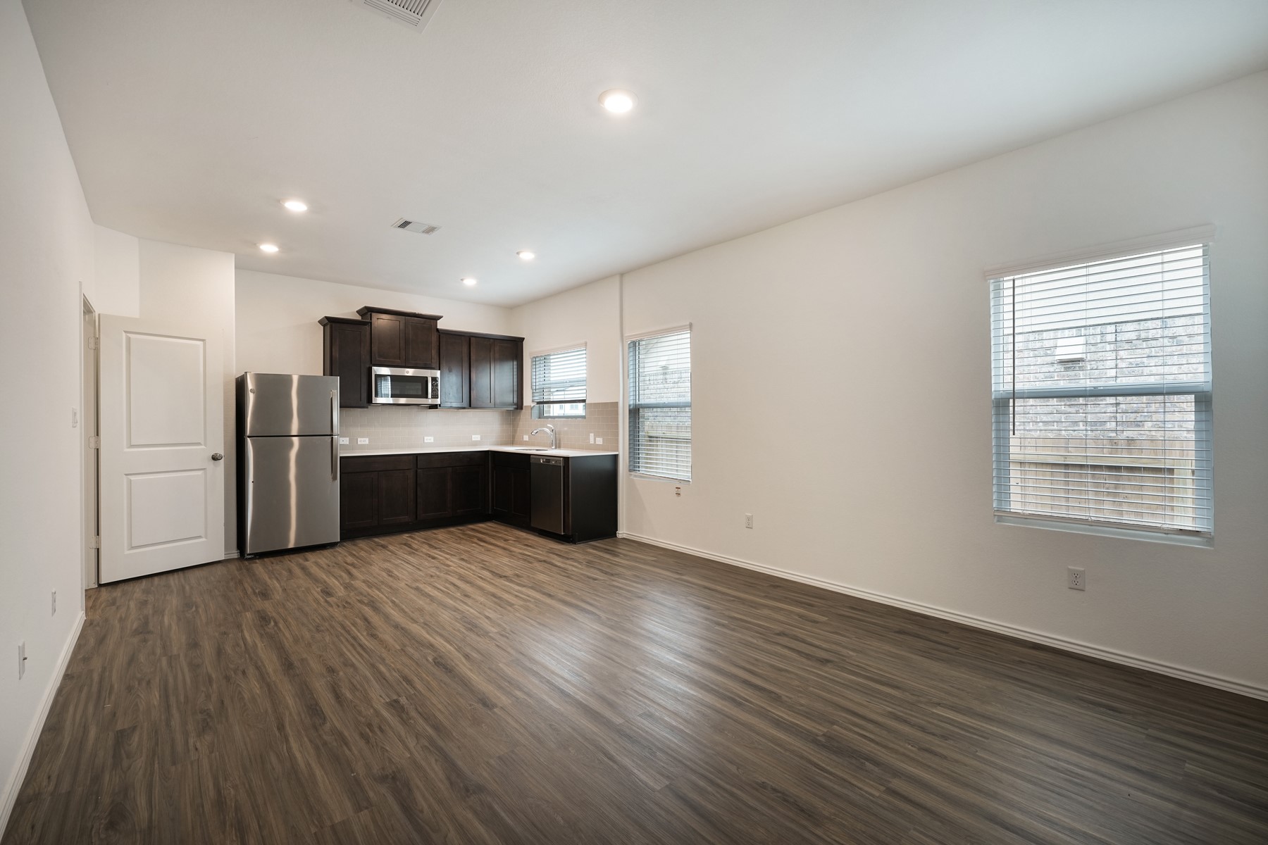 932 Mallow Road Leander, TX 78641 - Photo 8 of 34 A corner kitchen features dark cabinetry, stainless appliances, and a seamless flow into a versatile living space.