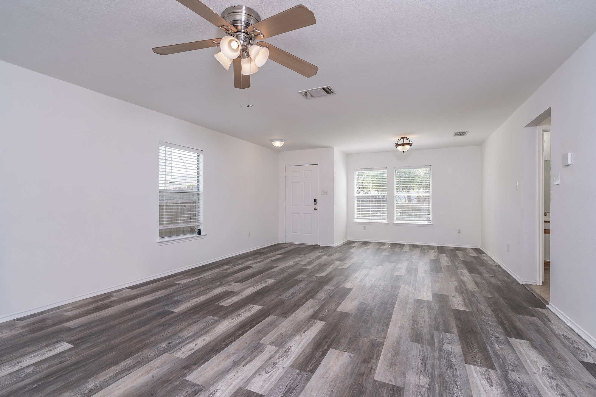 1305 Water Spaniel Way Round Rock, TX 78664 - Photo 9 of 27 an empty room with wooden floor ceiling fan and windows