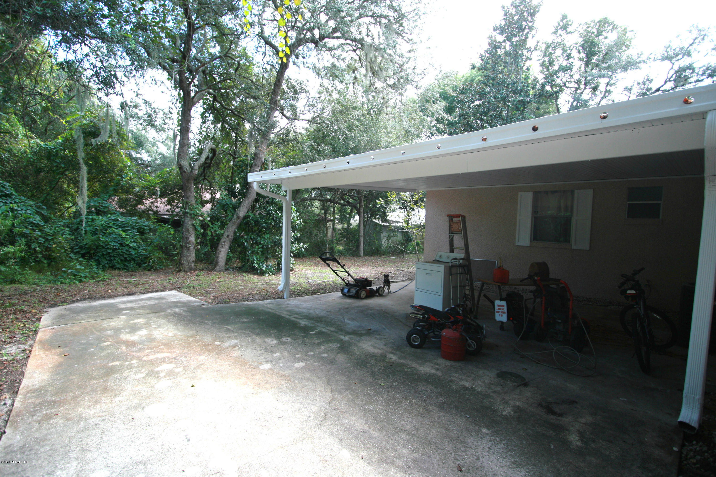 523 Gentian Road St. Augustine, FL 32086 - Photo 20 of 26 a view of a patio with table and chairs potted plants with large tree