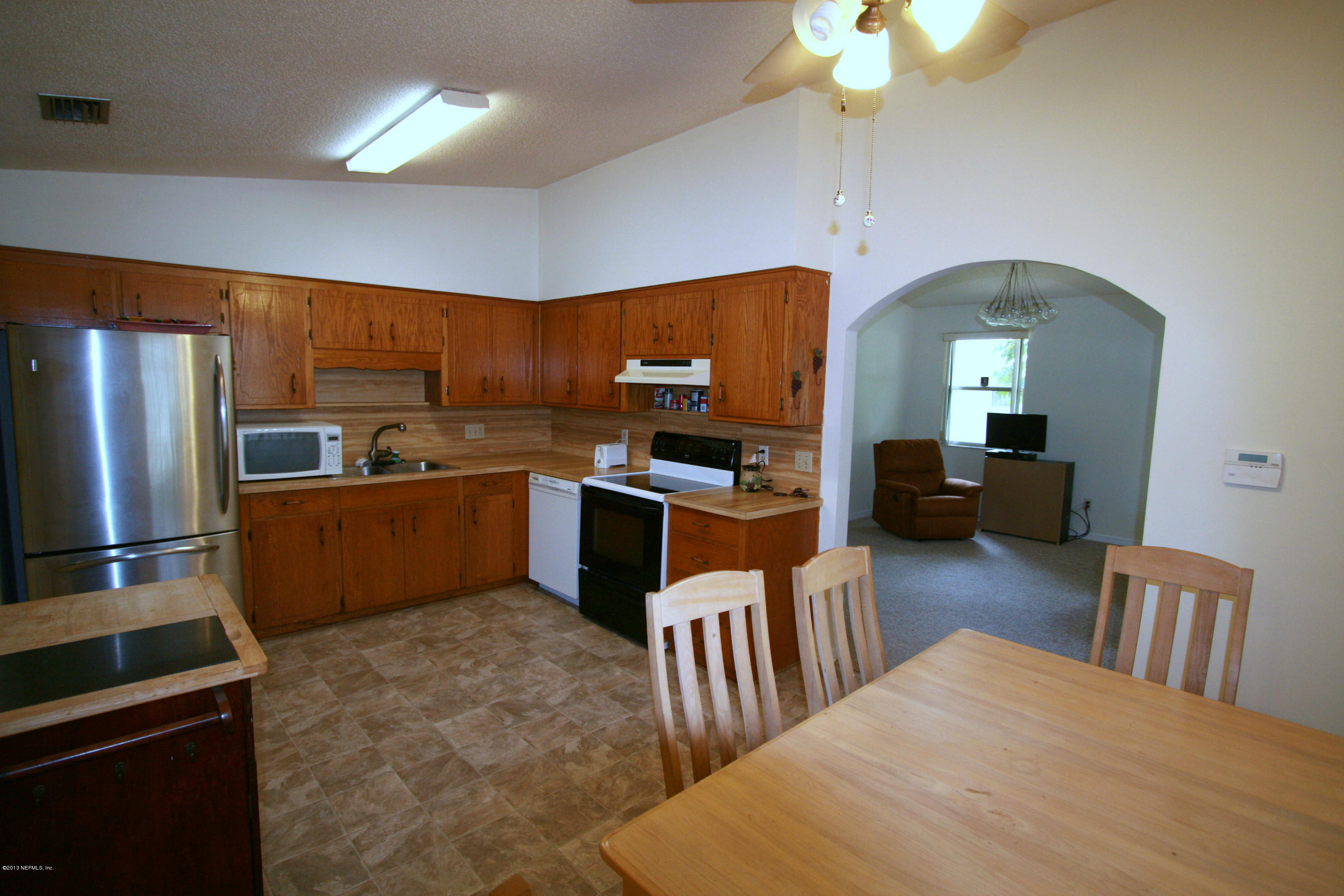 523 Gentian Road St. Augustine, FL 32086 - Photo 8 of 26 a kitchen with stainless steel appliances kitchen island granite countertop a refrigerator a sink dishwasher a stove and a dining table with wooden floor