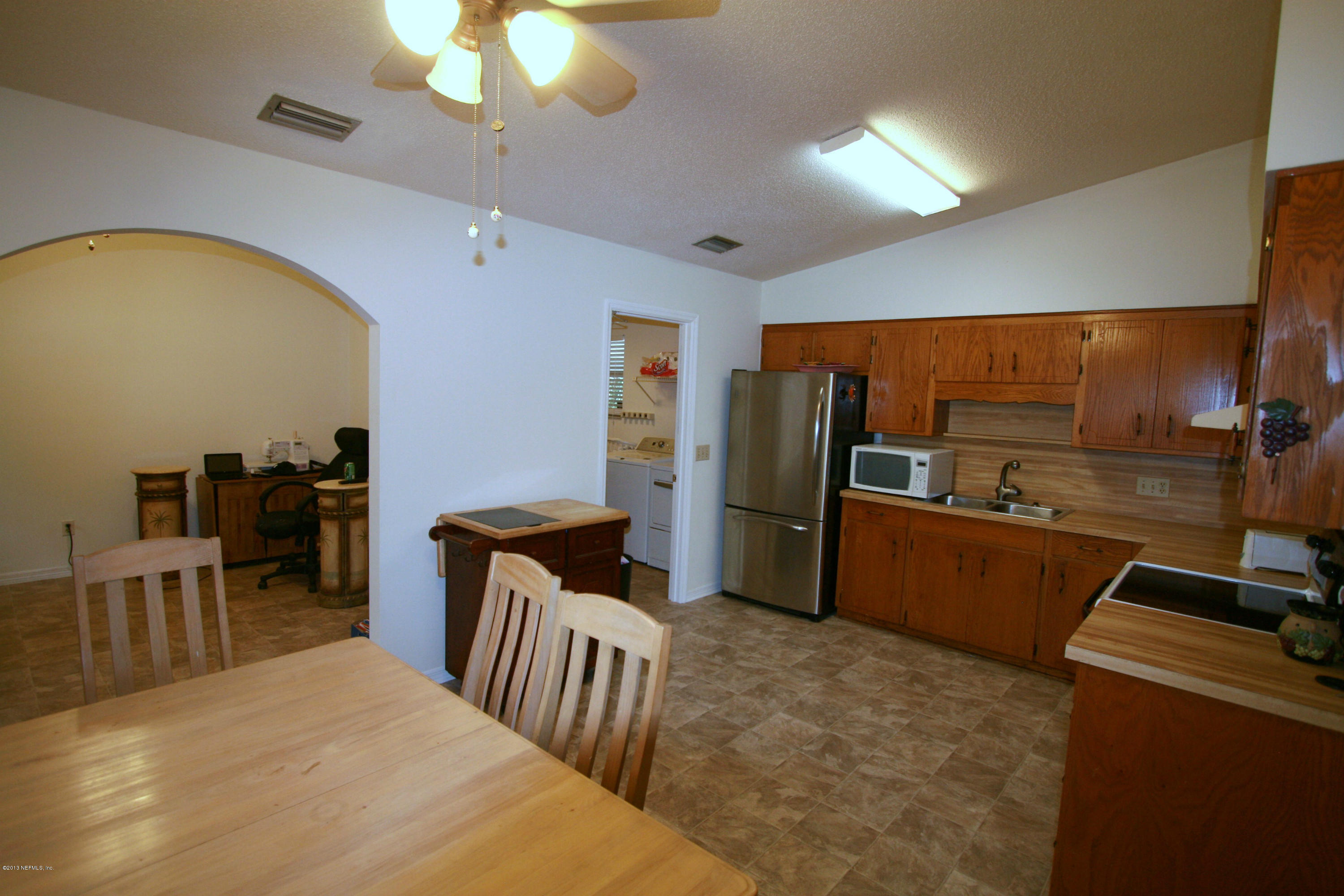 523 Gentian Road St. Augustine, FL 32086 - Photo 9 of 26 a kitchen with stainless steel appliances kitchen island granite countertop a refrigerator a stove a sink a dining table and chairs with wooden floor