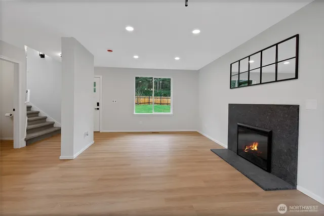 a view of an empty room with wooden floor fireplace and a window