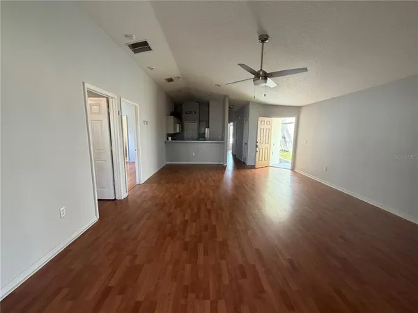 a view of a big room with wooden floor a ceiling fan and windows