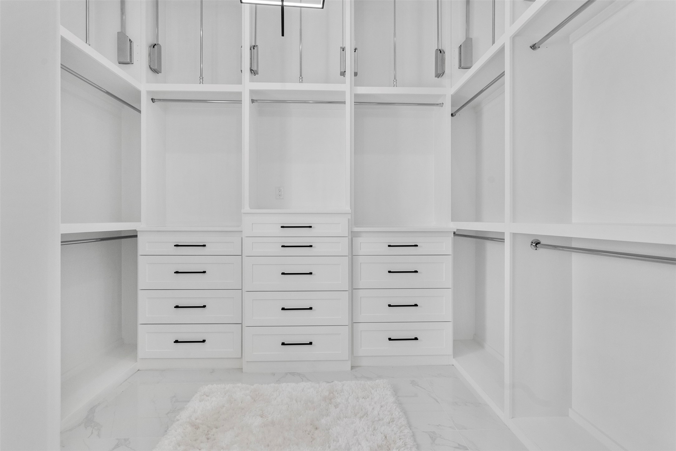 12 County Road 3558 Cleveland, TX 77327 - Photo 17 of 50 Spacious and custom primary closet with soaring ceilings, abundant hanging space, convenient drawers, and convenient pull-down rods for easy access to upper storage. Tons of shoe storage on the other side as well.