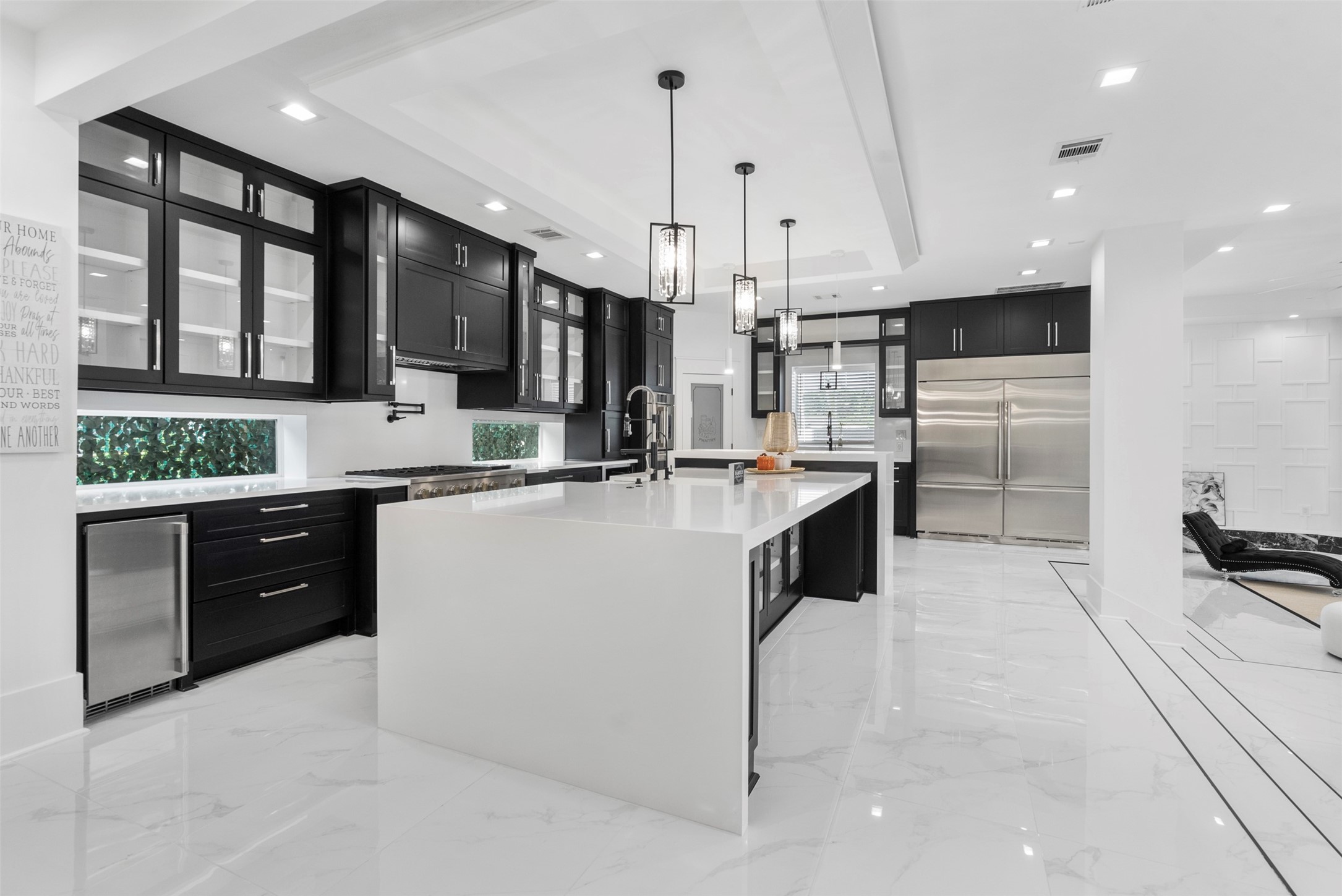 12 County Road 3558 Cleveland, TX 77327 - Photo 8 of 50 Alternate view of the kitchen highlighting the oversized island, abundant cabinetry, and a sleek double refrigerator for ample storage and functionality.