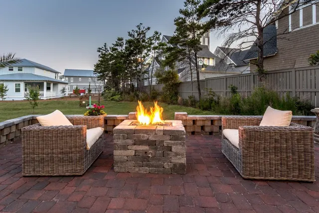 a view of a patio with couches table and chairs under an umbrella with a fire pit