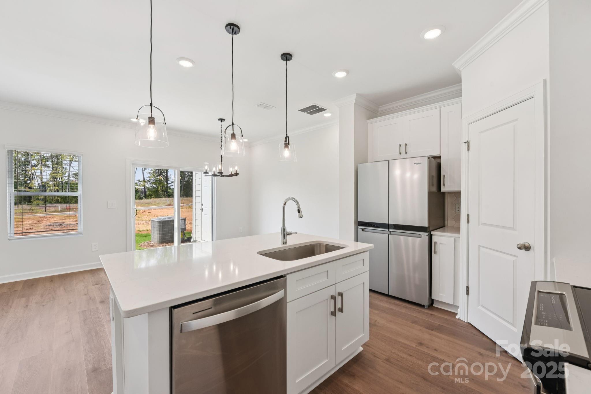 278 Tiger Lily Drive Fort Mill, SC 29708 - Photo 4 of 18 a kitchen with stainless steel appliances granite countertop a refrigerator a sink a stove and white cabinets with wooden floor