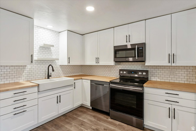 4746 South 700 East, Unit 91 Murray, UT 84107 - Photo 1 of 1 Kitchen with butcher block countertops, stainless steel appliances, white cabinets, backsplash, and recessed lighting