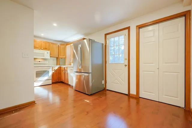 a view of a kitchen with refrigerator and wooden floor