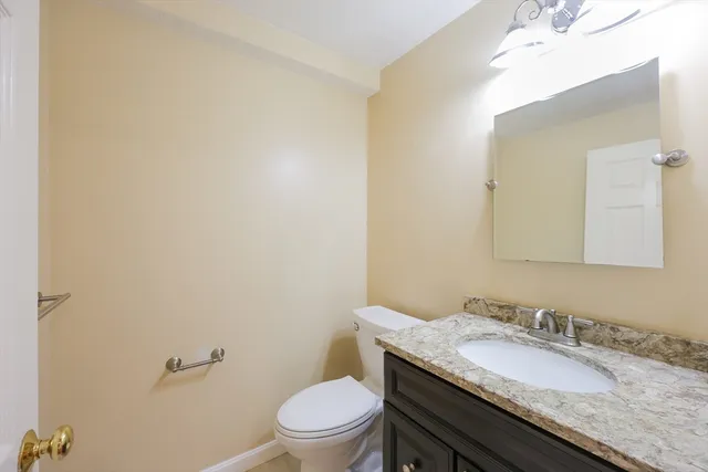 a bathroom with a granite countertop sink a toilet and a mirror