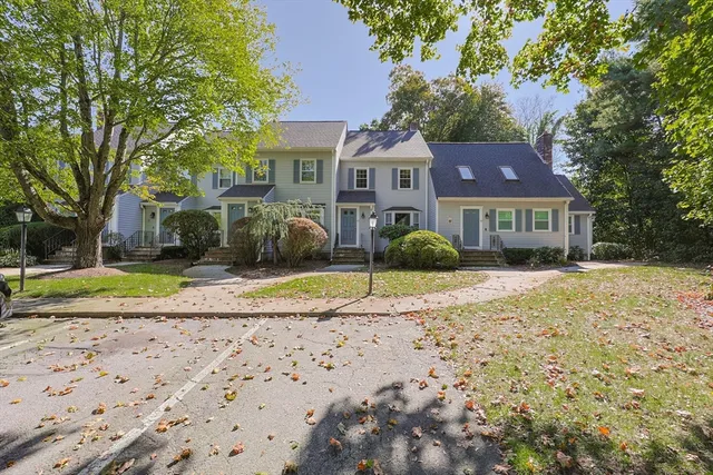 a view of a yard in front of a brick house with a fountain