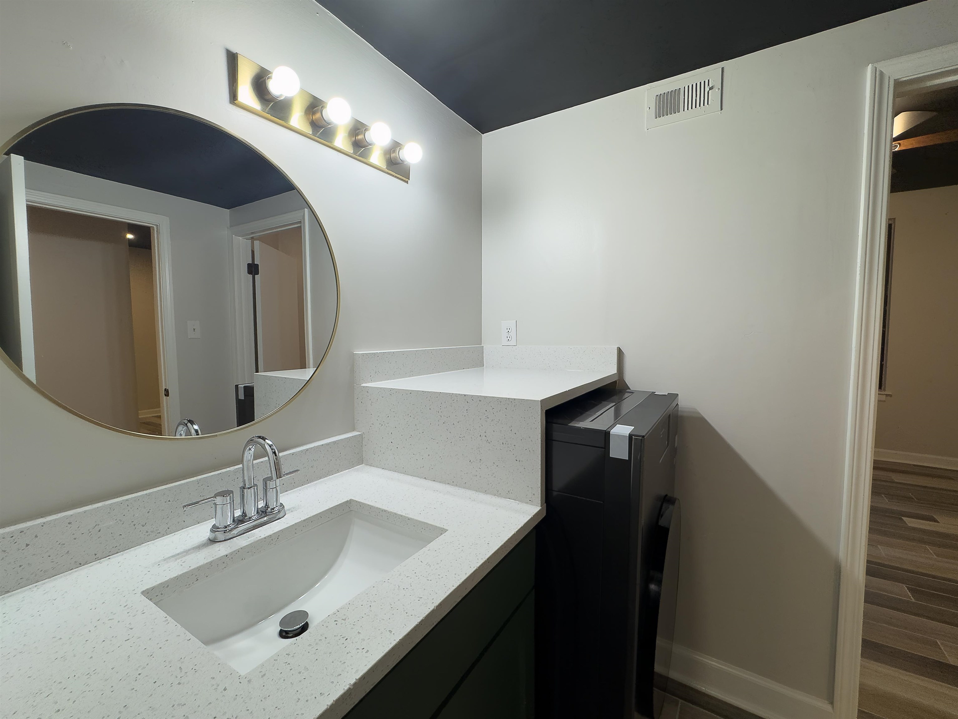 109 North Main Street, Unit 907 Memphis, TN 38103 - Photo 17 of 29 Bathroom vanity featuring a vessel sink, speckled countertop, and round mirror with a gold-tone frame