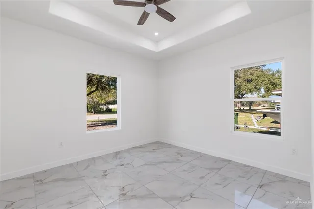 an empty room with windows and fan