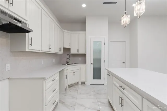 a kitchen with white cabinets and sink