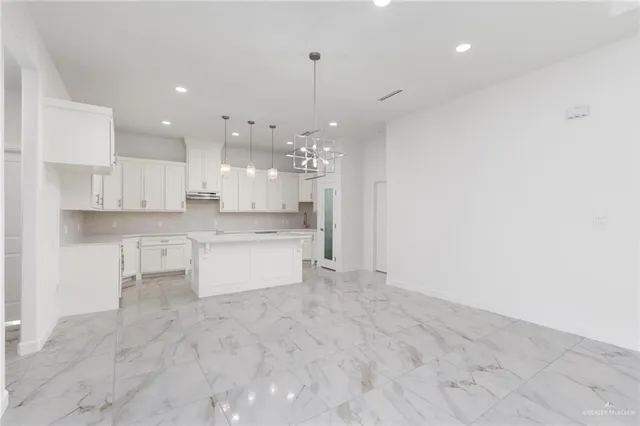 a large kitchen with a refrigerator a stove top oven and white cabinets