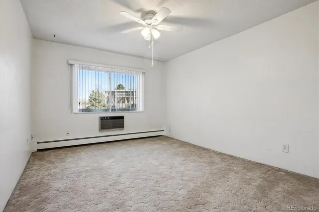 an empty room with chandelier fan and windows