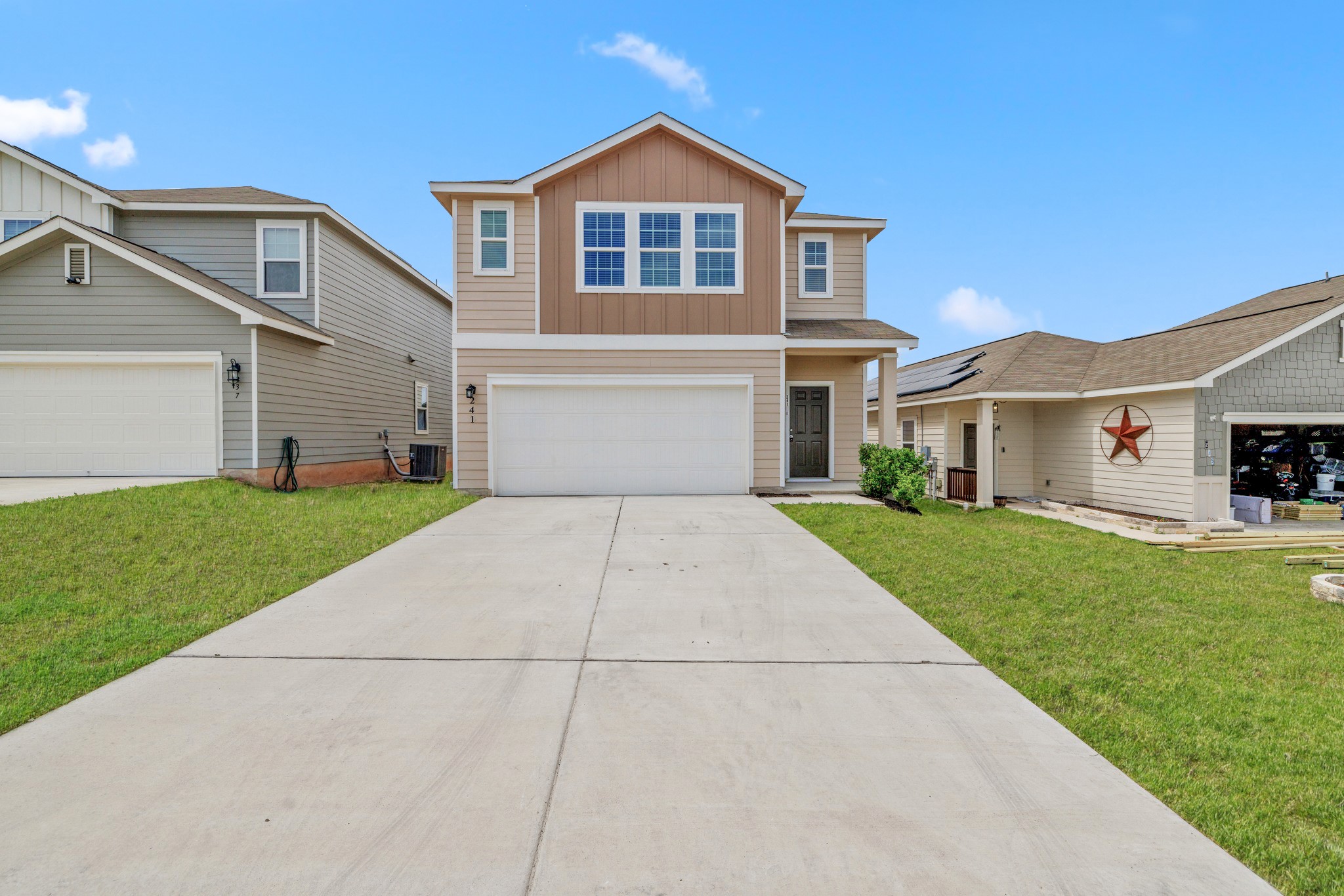 View of front facade featuring a front lawn, concrete driveway, an attached garage, and board and batten siding
