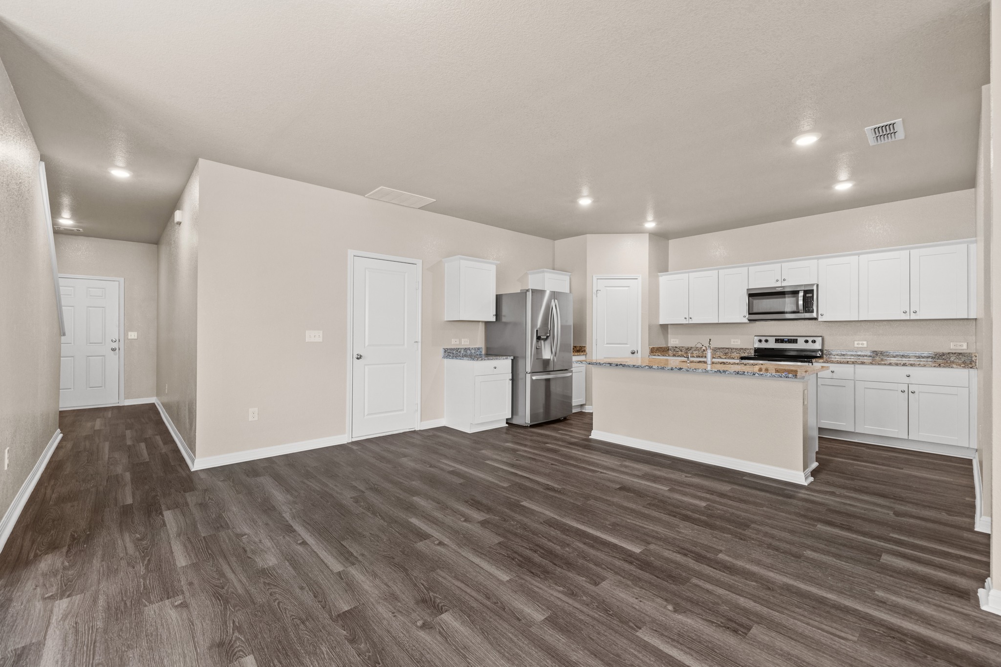 241 Night Riders Way Jarrell, TX 76537 - Photo 10 of 39 Kitchen featuring white cabinets, stainless steel appliances, an island with sink, dark wood-type flooring, and recessed lighting