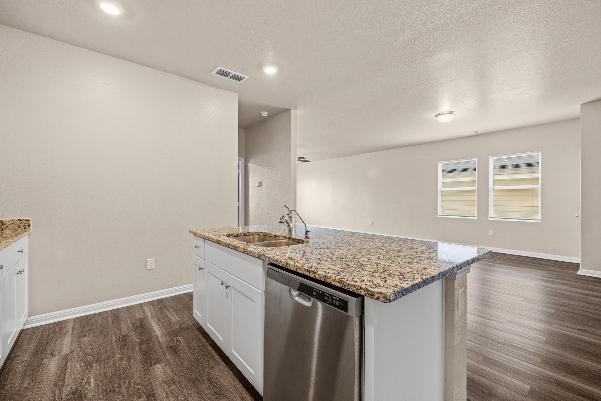 241 Night Riders Way Jarrell, TX 76537 - Photo 12 of 39 Kitchen with stainless steel dishwasher, light stone counters, white cabinetry, dark wood-style flooring, and a kitchen island with sink
