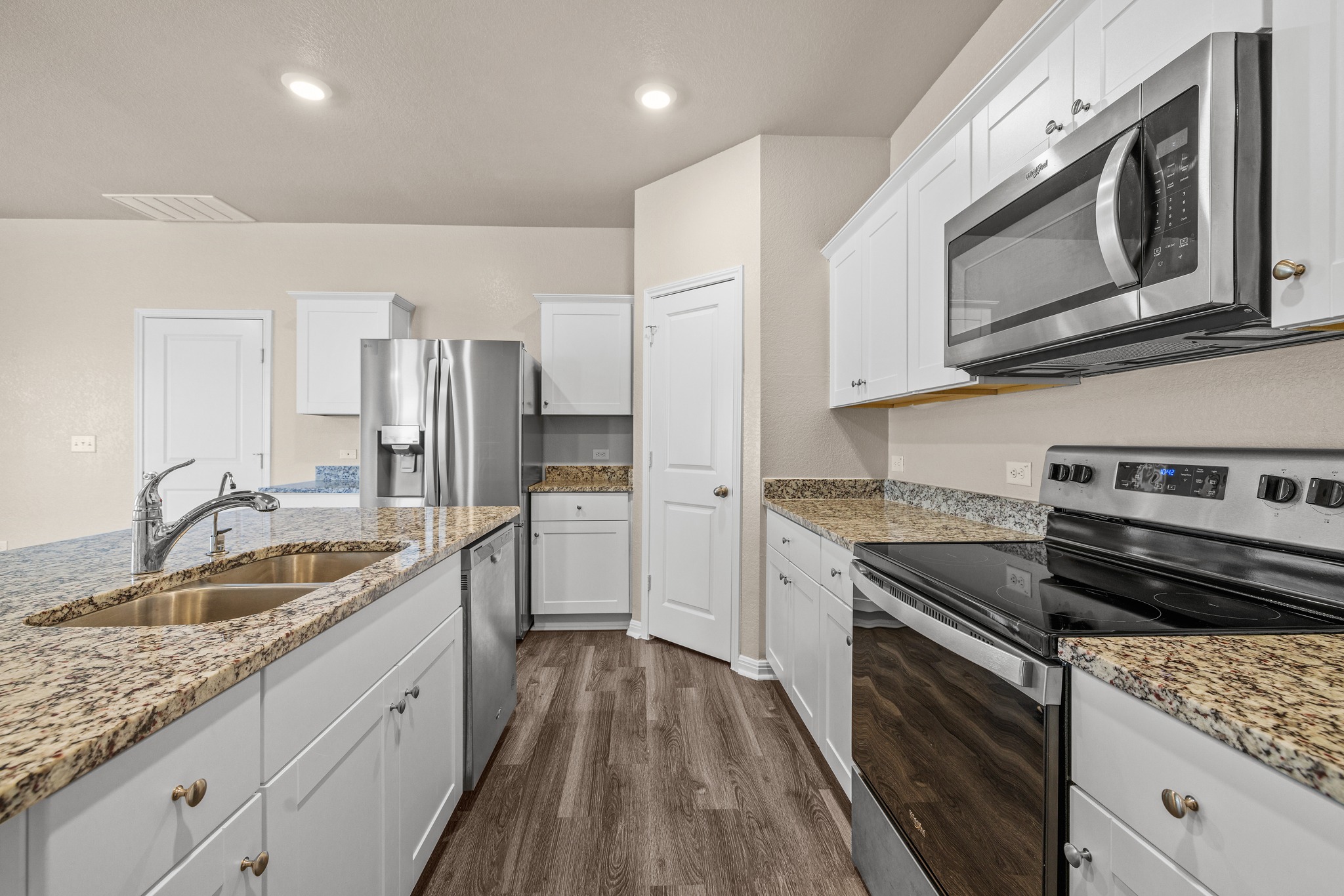 241 Night Riders Way Jarrell, TX 76537 - Photo 13 of 39 Kitchen featuring stainless steel appliances, white cabinetry, dark wood-style floors, light stone counters, and recessed lighting