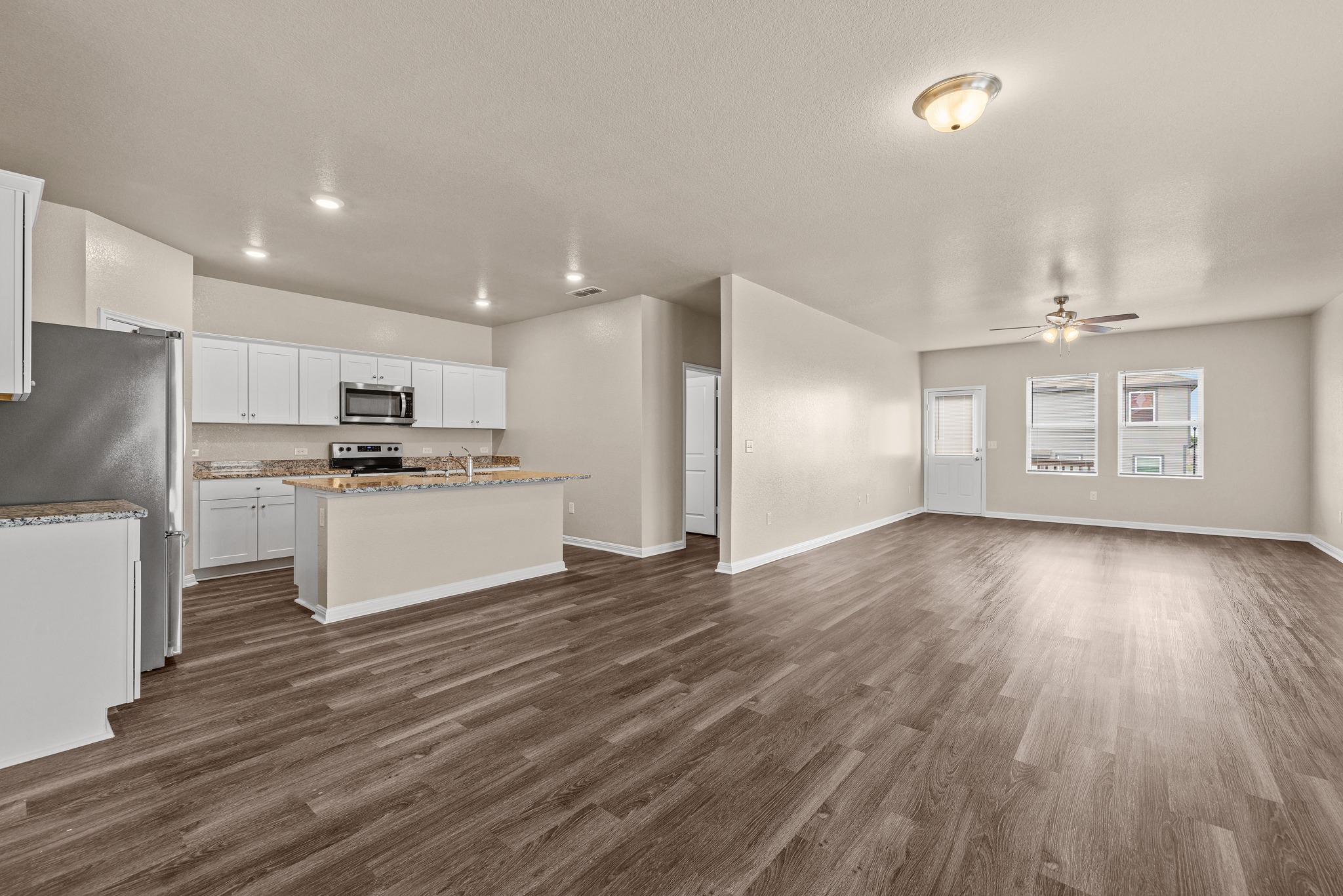 241 Night Riders Way Jarrell, TX 76537 - Photo 39 of 39 Kitchen with open floor plan, stainless steel appliances, white cabinetry, light stone countertops, and a center island with sink