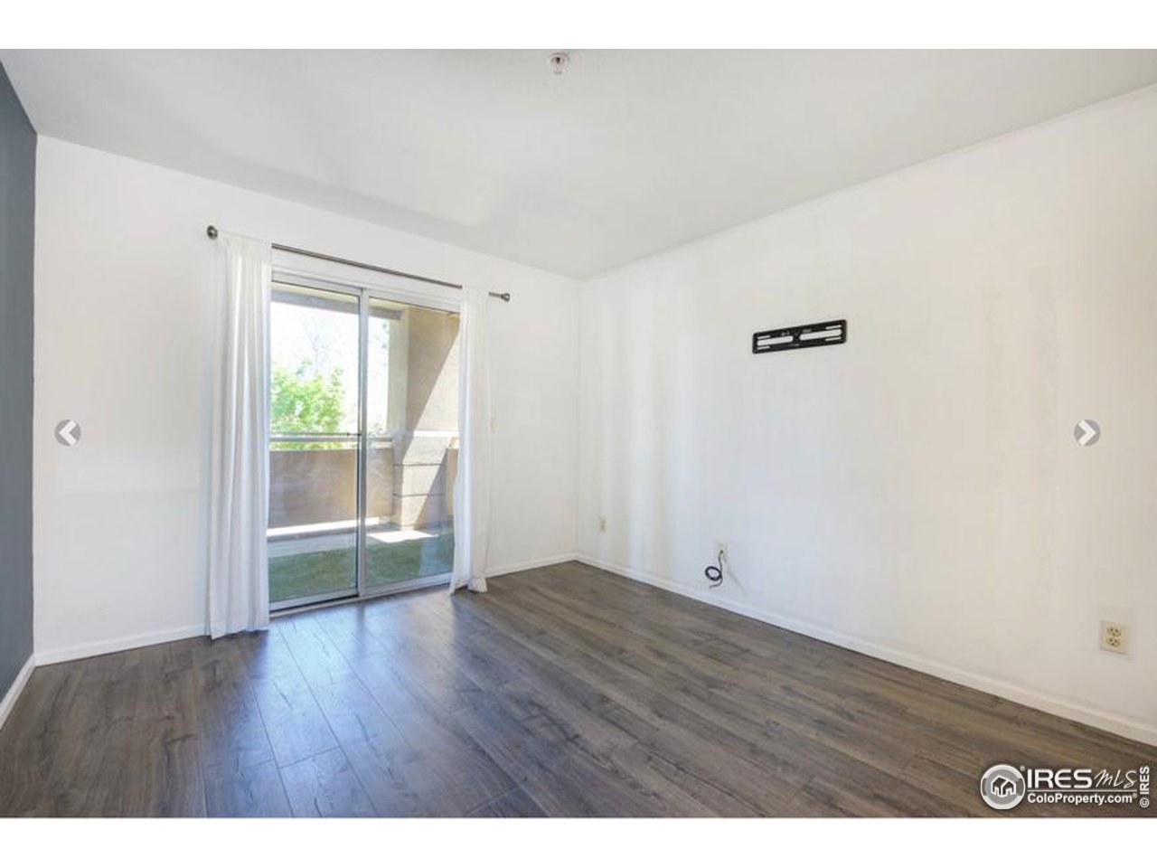 935 Broadway, Unit 106 Boulder, CO 80302 - Photo 14 of 34 a view of an empty room with wooden floor and a window