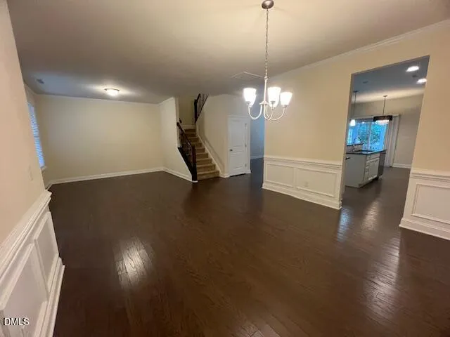 a view of an empty room with wooden floor and stairs