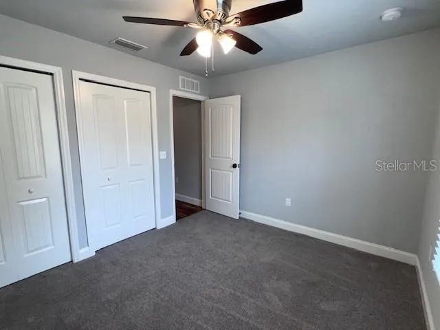an empty room with closet and a chandelier fan