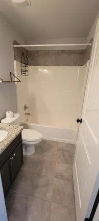 a bathroom with a granite countertop sink a toilet and bathtub