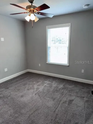 an empty room with a window and a fan