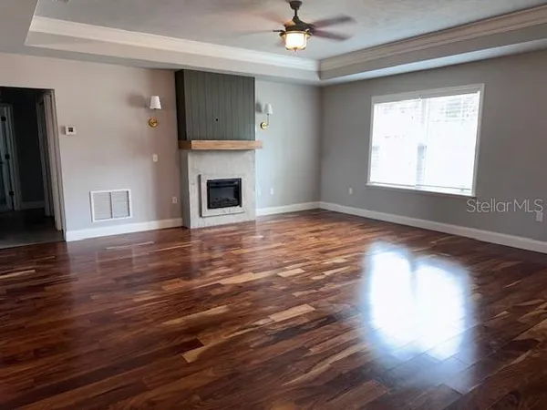 a view of empty room with wooden floor and fan