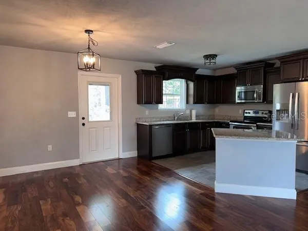 a kitchen with stainless steel appliances kitchen island granite countertop a stove a sink and a refrigerator