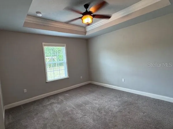 an empty room with window and a chandelier fan