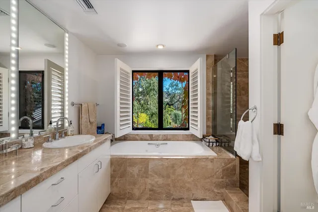 a spacious bathroom with sinks mirror and a bathtub