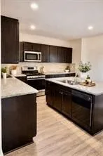 a kitchen with stainless steel appliances a sink dishwasher a stove and a microwave oven on wooden floor