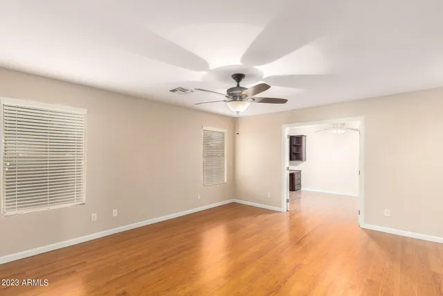 an empty room with wooden floor and ceiling fan