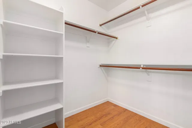 an empty room with wooden floor closet and windows