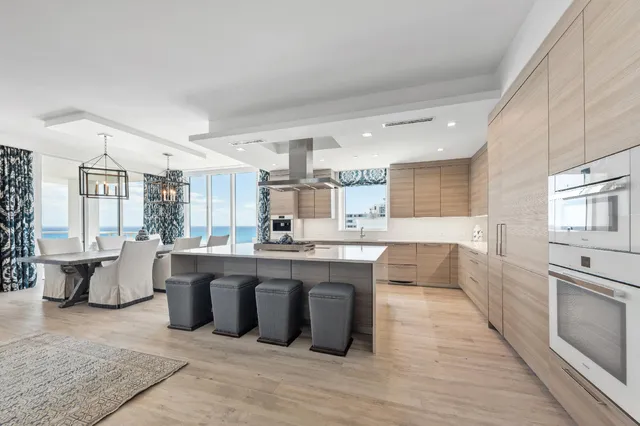 a large white kitchen with wooden floor and stainless steel appliances