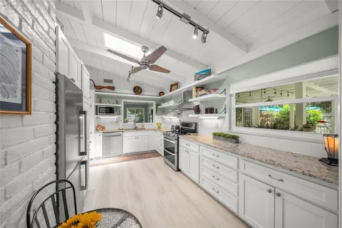 a kitchen with stainless steel appliances granite countertop a refrigerator a stove oven and white cabinets with wooden floor