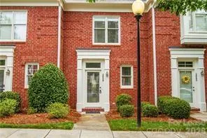 front view of a brick house with a yard and plants