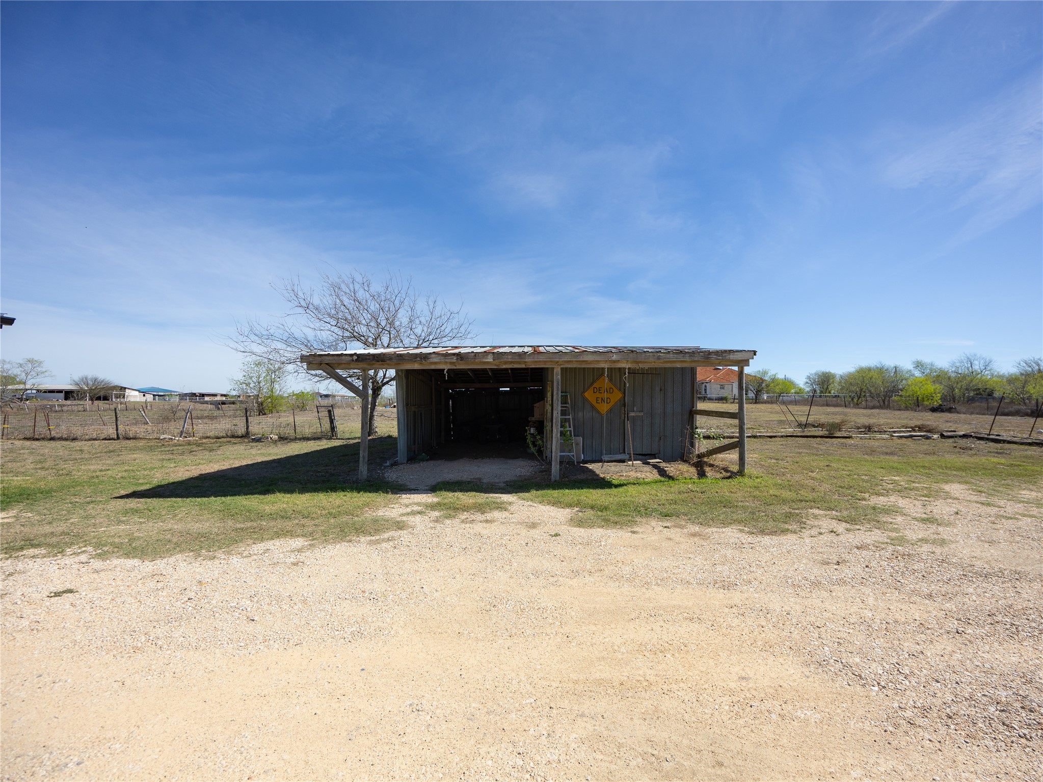 2412 Williamson Road Lockhart, TX 78644 - Photo 12 of 36 Freestanding utility structure with a metal roof and open-bay design, featuring a gravel approach and a surrounding grassy area