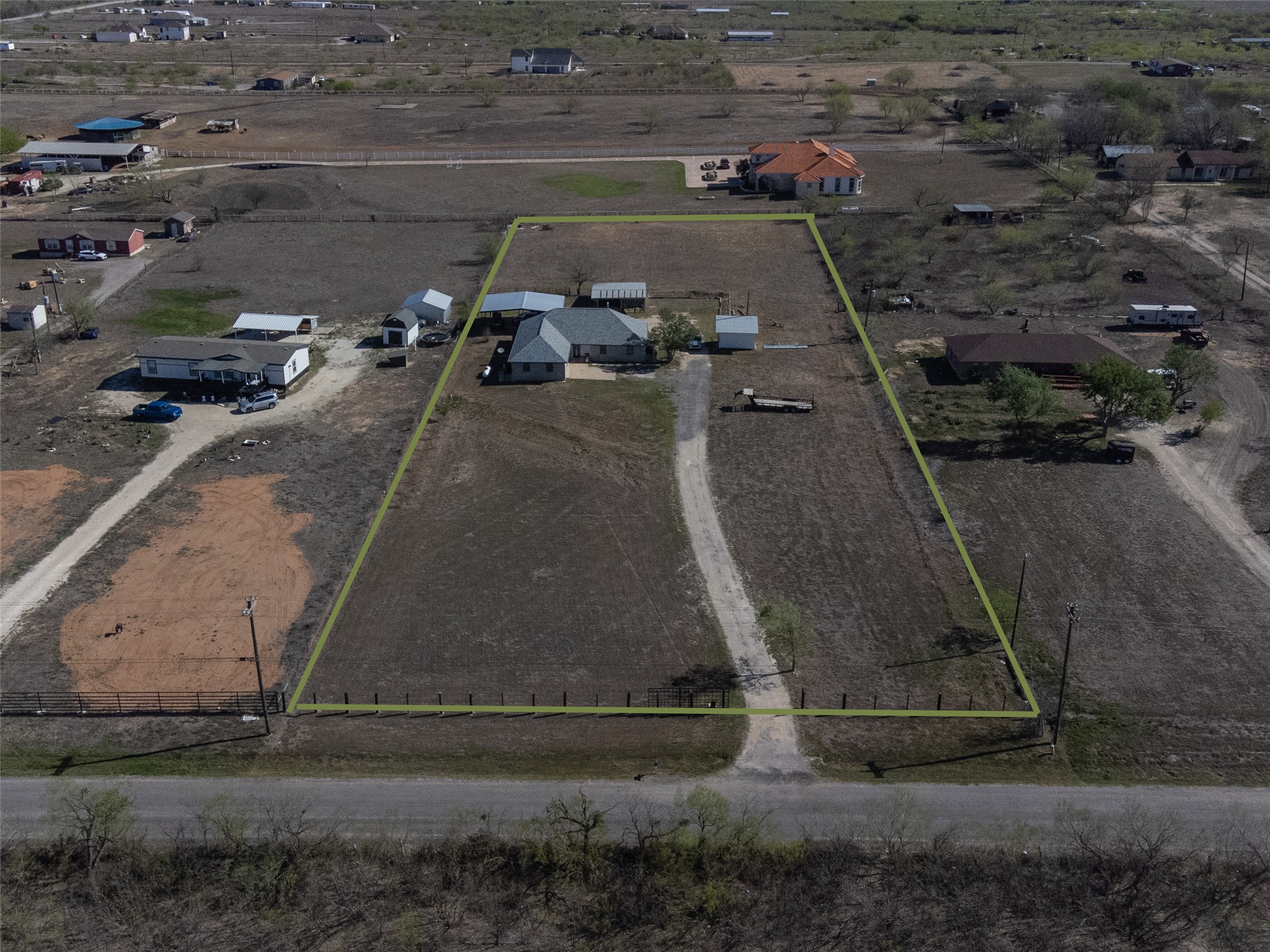 2412 Williamson Road Lockhart, TX 78644 - Photo 2 of 36 Expansive rural property featuring a primary residence with an attached garage, a separate detached structure, and a long gravel driveway