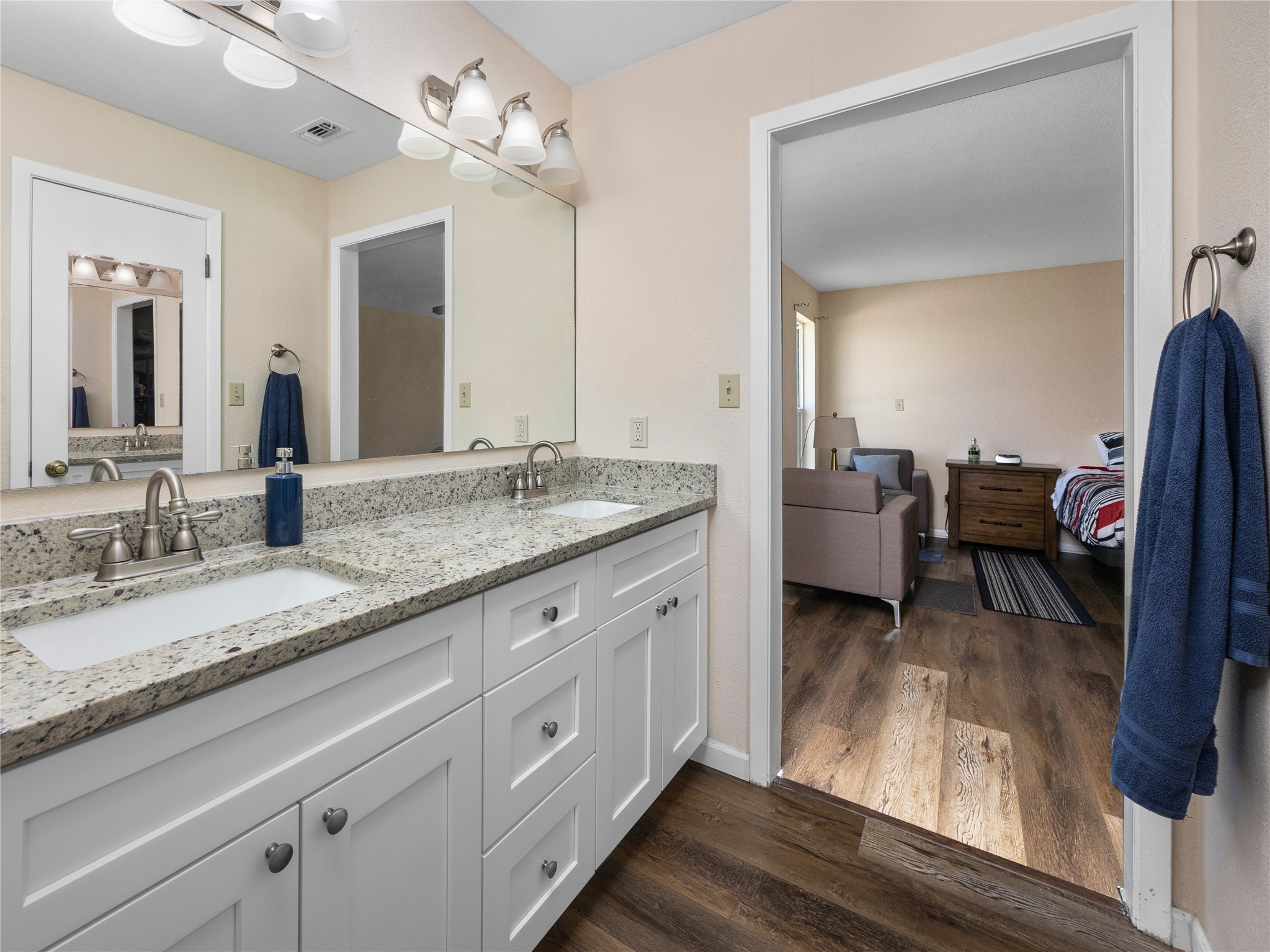 2412 Williamson Road Lockhart, TX 78644 - Photo 22 of 36 Bathroom vanity featuring dual undermount sinks, stone-finish countertop, white cabinetry with silver hardware, and a large wall-mounted mirror