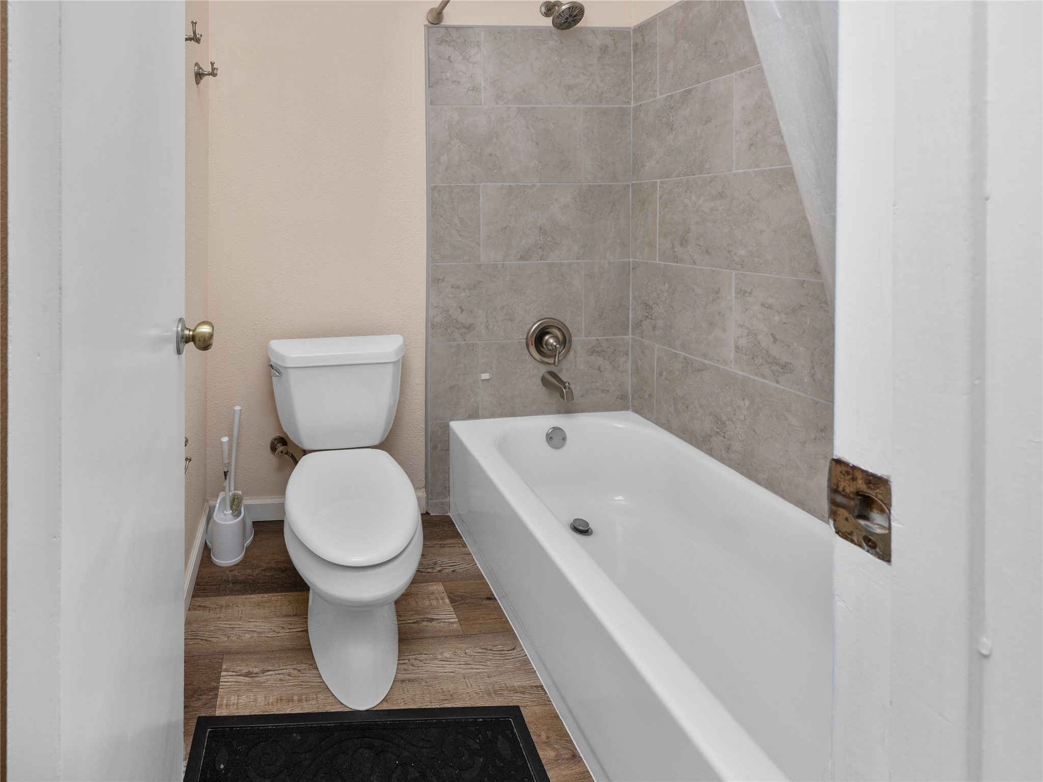 2412 Williamson Road Lockhart, TX 78644 - Photo 24 of 36 Bathroom featuring a white bathtub, tiled shower surround, and wood-finish flooring