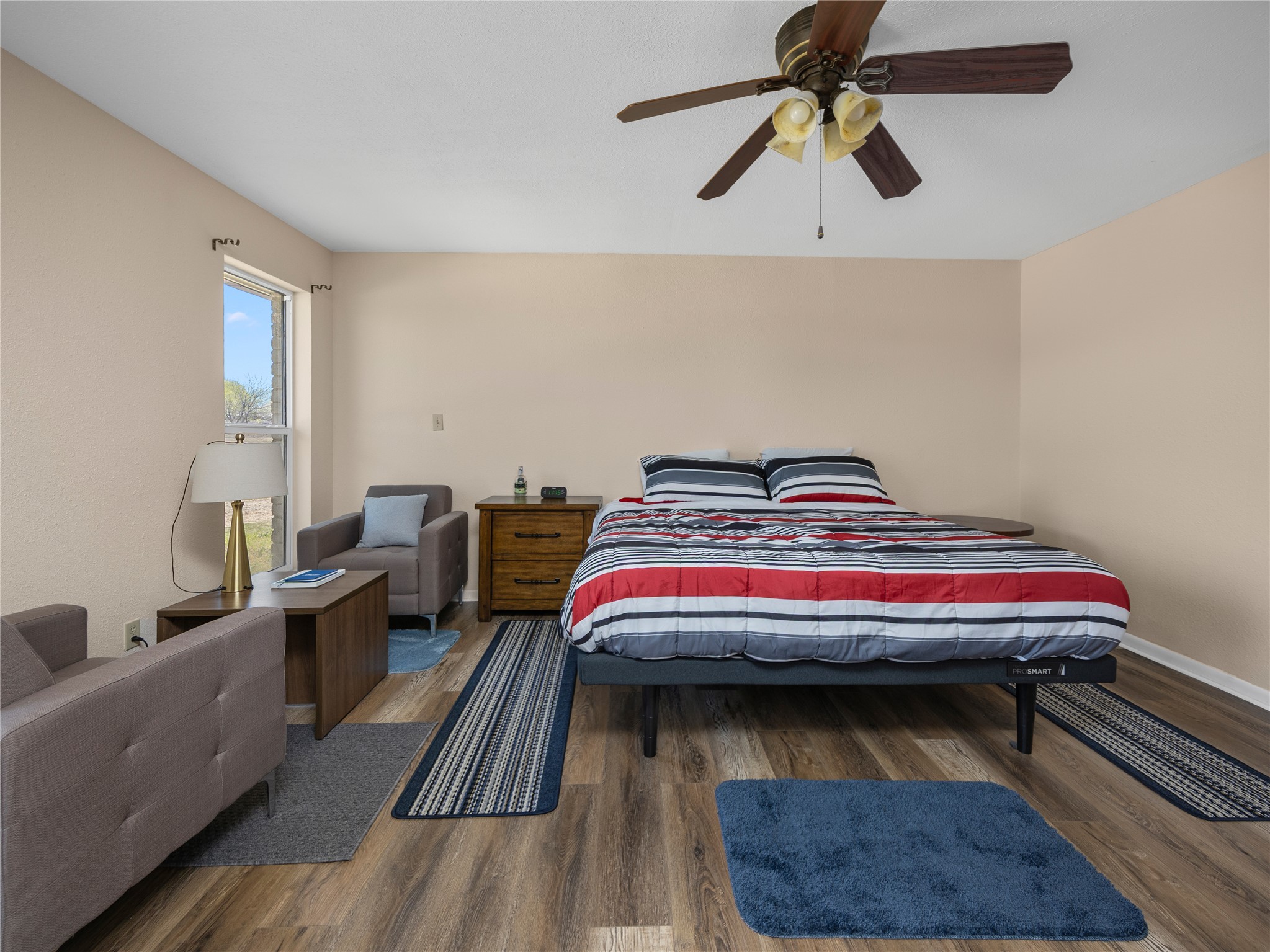 2412 Williamson Road Lockhart, TX 78644 - Photo 27 of 36 Spacious room featuring wood-finish flooring, a ceiling fan with integrated lighting, and a large window providing natural light