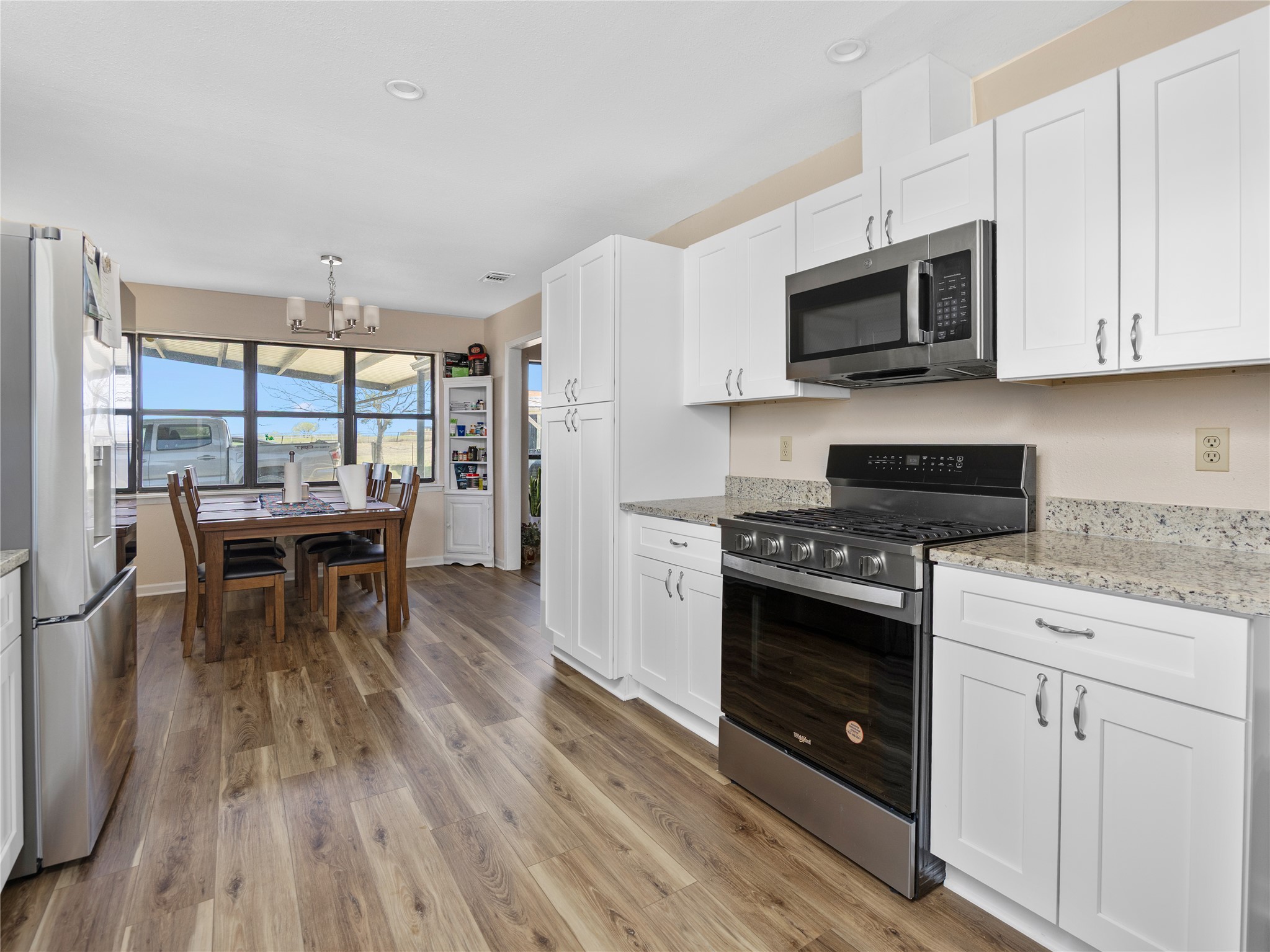 2412 Williamson Road Lockhart, TX 78644 - Photo 29 of 36 Modern kitchen featuring wood-finish flooring, white cabinetry, stainless steel appliances, and light-toned countertops