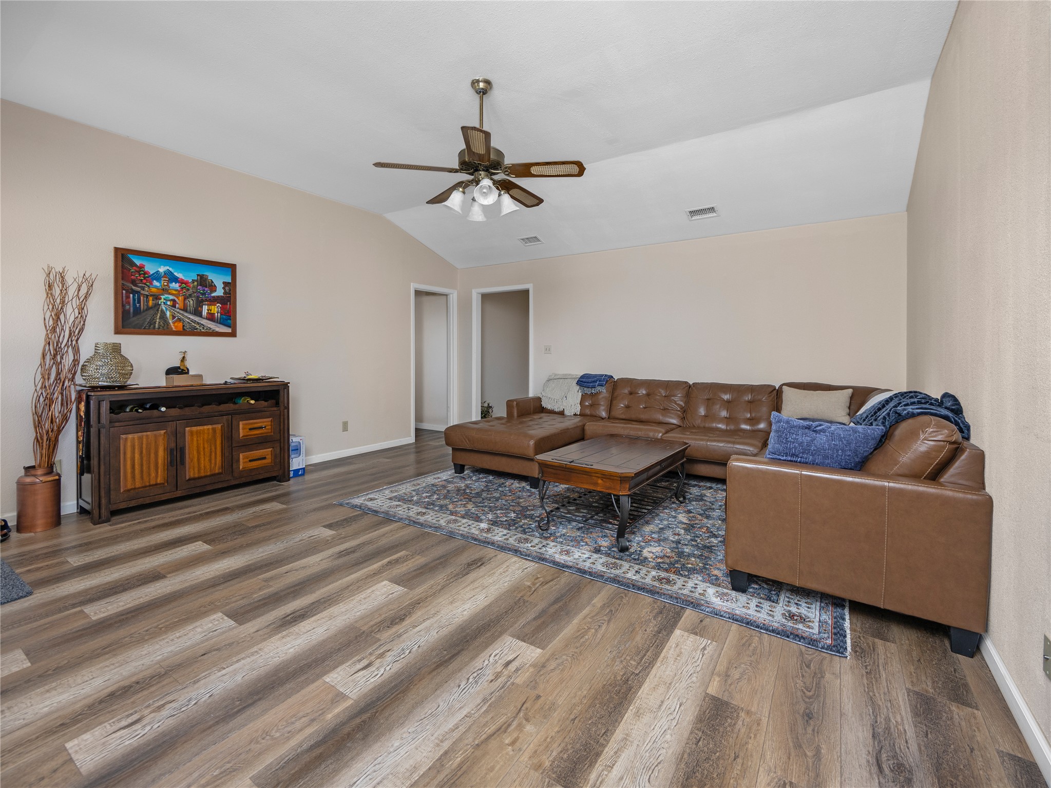 2412 Williamson Road Lockhart, TX 78644 - Photo 31 of 36 Spacious living area featuring vaulted ceilings, wood-finish flooring, a ceiling fan with integrated lighting, and a built-in credenza