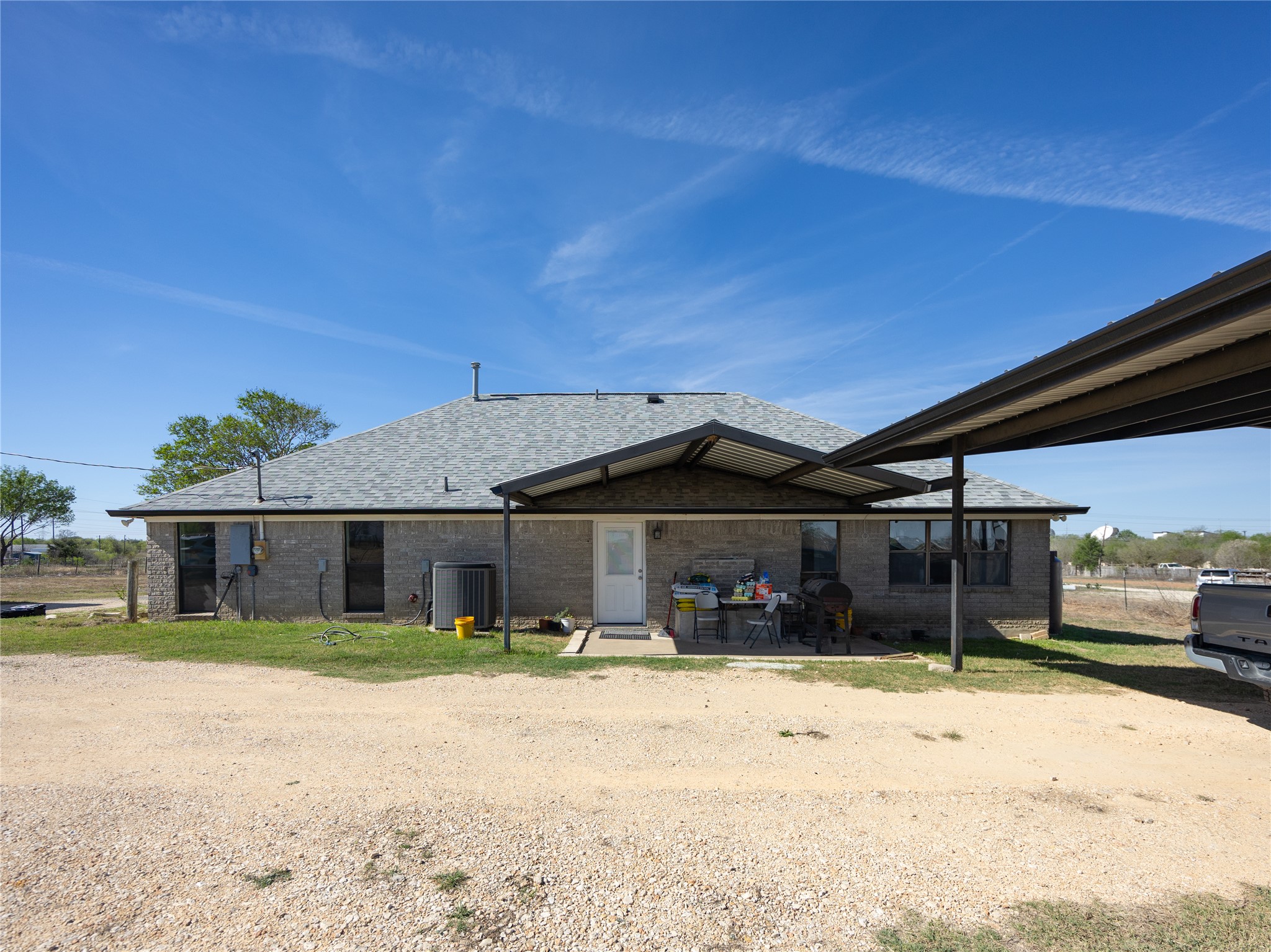 2412 Williamson Road Lockhart, TX 78644 - Photo 32 of 36 Rear exterior featuring a covered patio, a full-length covered carport, and a gravel yard