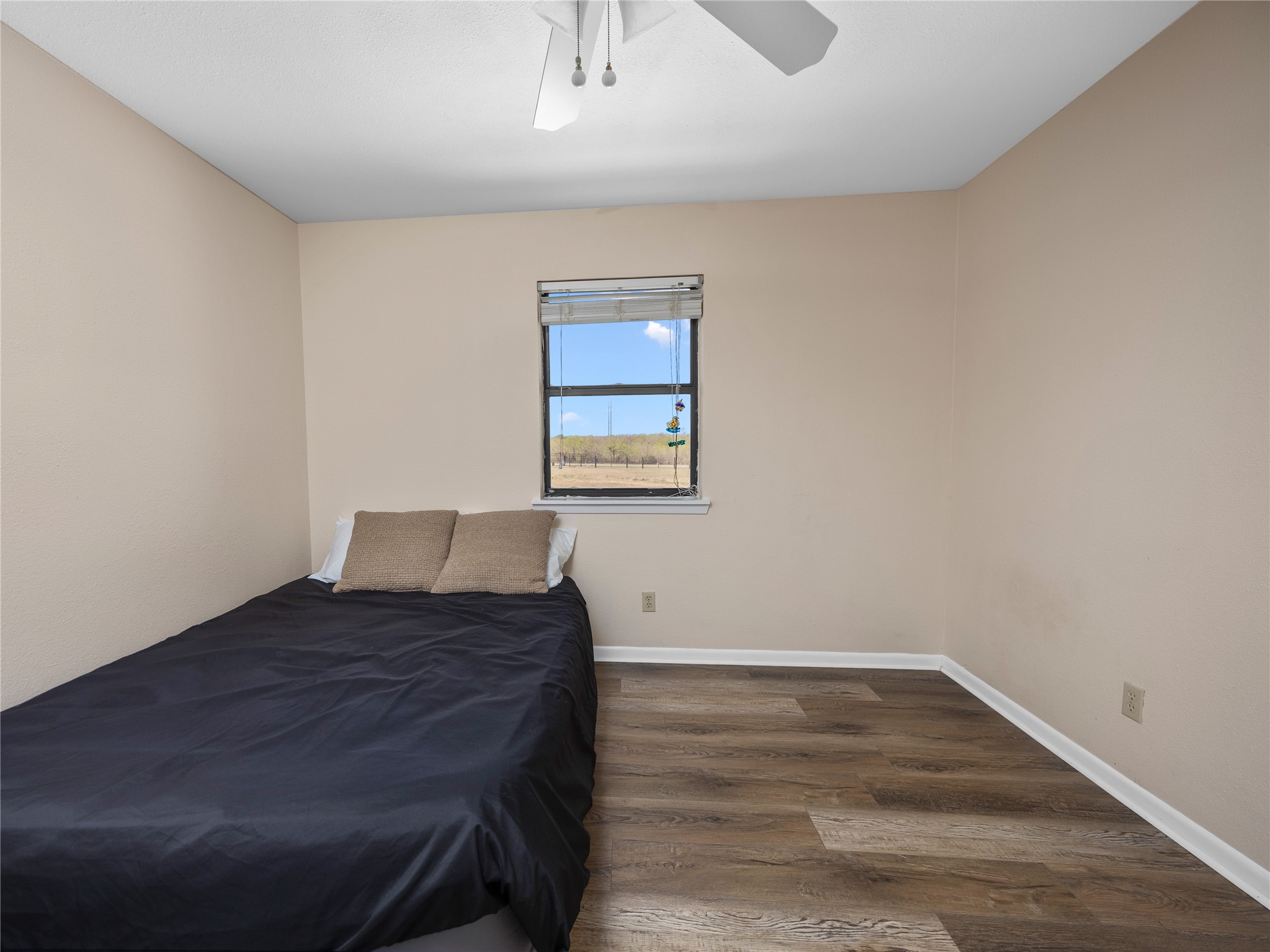 2412 Williamson Road Lockhart, TX 78644 - Photo 35 of 36 Room featuring wood-finish flooring, neutral wall tones, a window with blinds, and a ceiling fan