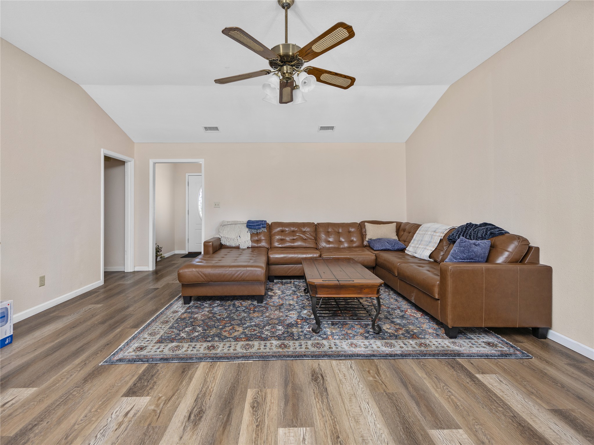 2412 Williamson Road Lockhart, TX 78644 - Photo 4 of 36 Spacious living area featuring wood-finish flooring, vaulted ceilings, a ceiling fan with integrated lighting, and neutral wall tones